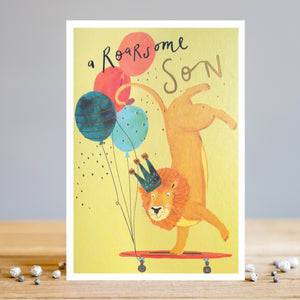 This birthday card for a special son is decorated with an illustration by artist Louise Tiler showing a featuring a lion wearing a crown, balancing on its front paws on a skateboard decorated with a bunch of balloons. The caption on the front of the card reads "a Roarsome Son".