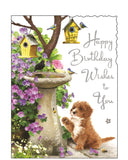 This adorable Jonny Javelin birthday card features a sweet cockapoo watching curiously as a snail slowly climbs up a stone birdbath, while cheerful birds flutter around nearby birdhouses. Set in a charming garden scene, this beautifully illustrated card is full of gentle humour and heartwarming detail. Silver text on the card reads "Happy Birthday Wishes to You".