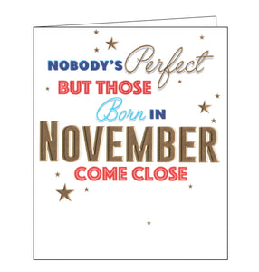 This birthday card is decorated with red, blue and gold script that reads "Nobody's perfect but those born in November come close". Embossed gold stars are sprinkled around the text.