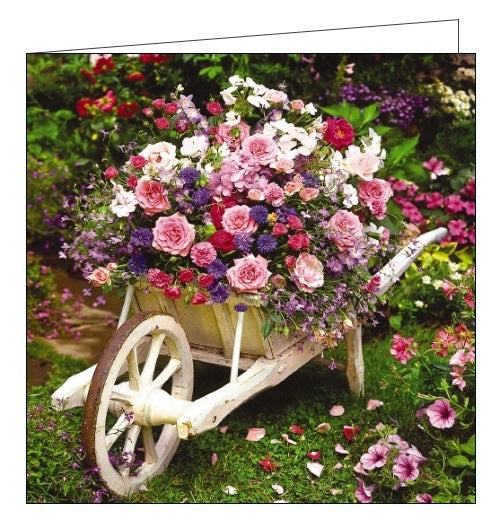This blank card is decorated with a photograph of a wooden wheelbarrow planted with pink, purple and white flowers.