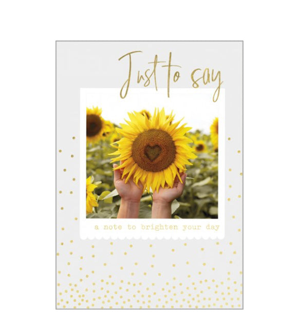 Perfect for many occasions - just to keep in touch, get well, or thinking of you this cheerful card shows a sunflower with a heart shape in the middle. Gold text reads “Just to say