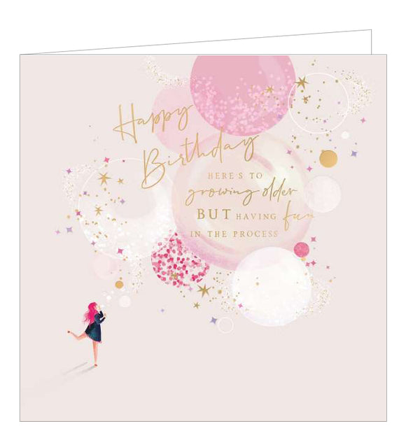 This beautiful birthday card features a sketch of a young woman with bright pink hair blowing bubbles, with large bubbles floating off in the background against a pink backdrop. Gold text on the front of the card reads 