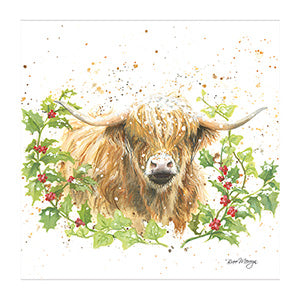 Logan the Highland Cow looks out from a holly hedge as the snow falls, on this beautiful Christmas card designed by Bree Merryn.