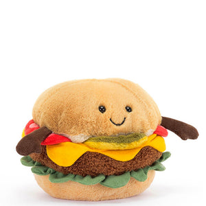Jellycats amusable burger has a soft squishy tan-coloured bread bun, sliced in half and filled with with a slice of tomato, gerkin, cheese, lettuce and a fluffy brown burger. The top of the burger bun has a cute embroidered smile and a pair of little black eyes