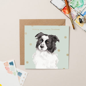 This charity Christmas card features a watercolour portrait of Spy, a border collie dog, surrounded by gold snowflakes. Gold text on the front of this Christmas card reads "Wishing you a Merry Christmas".&nbsp;