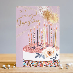 This birthday card for a special daughter is decorated with an off-centred illustration of a beautiful birthday cake topped with sparklers, birthday candles, a white rose, and multi-coloured sprinkles. Gold text on the front of the card reads "To a wonderful Daughter".