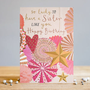 The perfect birthday card to show your sister how much you love her! This birthday card is decorated in a contemporary style, with a display of pink and gold star, pom-pom and heart hanging party decorations. Metallic text on the front of the card reads "So lucky to have a Sister like you...Happy Birthday".