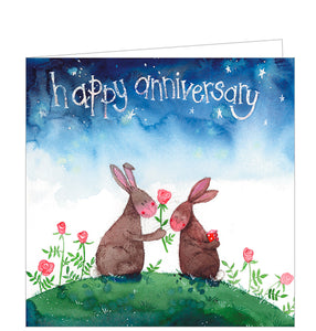 This cute anniversary card from Alex Clark is decorated with a pair of rabbits sitting together on a hillside under an inky night sky. One rabbit holds out a red rose to the other who is holding a wrapped present behind their back. The text on the card reads "Happy Anniversary".