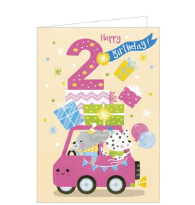 A bright, lively birthday card for a 2 year old is decorated with a cartoon of two dogs driving a pink car loaded with presents. The text on the front of the card reads "2...Happy Birthday!"