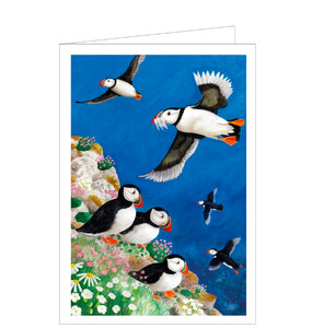 This beautiful blank greetings card is decorated with an artwork by Bex Parkin showing a flock of puffins perching on a cliff by the sea. Some of the birds are flying back after hunting for fish. Bold colour and strong design make this a stunning card for any occasion or message.