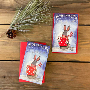 This pack of 5 thank you Christmas cards from Alex Clark features a festive rabbit holding a red and white gift box on a starry blue background. The silver text expresses gratitude with the words "Thank you".