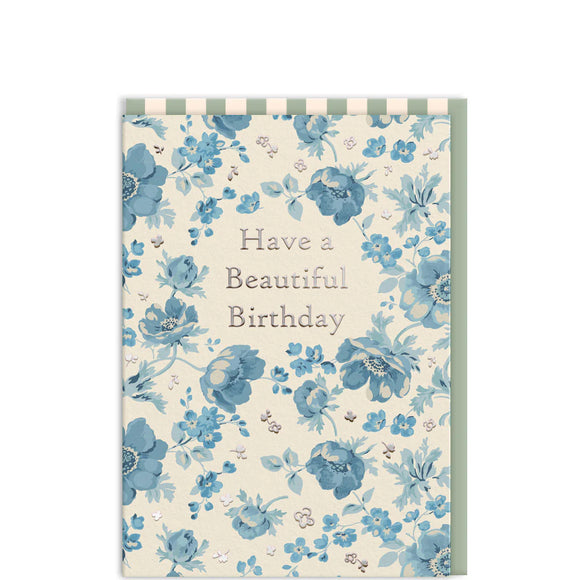 This charming birthday card is adorned with delicate blue florals, a signature of Cath Kidston's designs. The front features elegant silver text that reads 