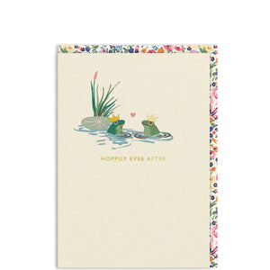 Something different for an engagement card or wedding card from a Cath Kidston design, showing two happy frogs wearing gold crowns are sitting in their pool, with a tiny heart floating in the air between them. Gold text on the front of the card reads "Hoppily ever after".&nbsp;