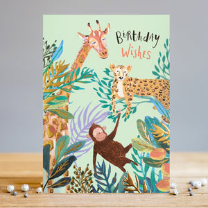 This Louise Tiler birthday card is sure to bring a smile to any youngster. Decorated with a fun jungle scene composed of a cartoon monkey, cheetah, and giraffe amid lush green foliage and gold details, the text on the front of the card reads "Birthday Wishes".