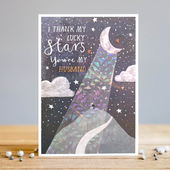 Perfect for birthdays, anniversaries or just-because this beautiful greetings card by Louise Tiler is decorated with a scene of a couple sitting on a mountain top under the night sky with stars, clouds, and an iridescent ray of moonlight, it's truly out of this world. Text on the front of the card reads 