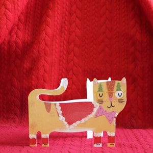 This adorable and unusual christmas card is cut into the shape of a cute ginger cat dressed for a christmas party in a cape, pink bowtie and a pair of christmas tree novelty glasses.