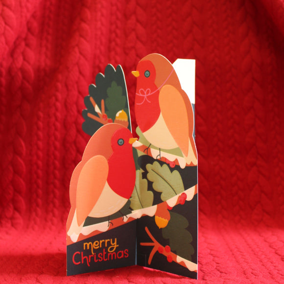 This unusual christmas card unfolds to create a 3d pop up scene of a pair of robins perched on the branches of a snowy oak tree, ripe with berries and acorns. The caption on the front of the card reads 