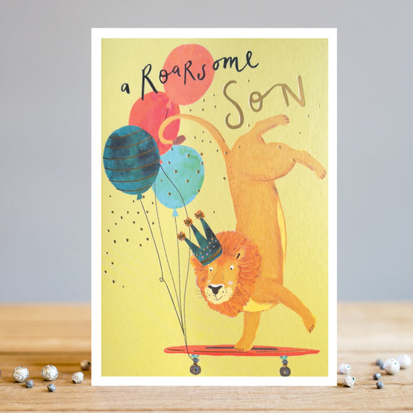This birthday card for a special son is decorated with an illustration by artist Louise Tiler showing a featuring a lion wearing a crown, balancing on its front paws on a skateboard decorated with a bunch of balloons. The caption on the front of the card reads 
