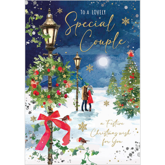 This stunning Jonny Javelin Christmas card for a special couple is decorated scene of a couple, wrapped up warmly against the cold and snow, paused to kiss under a victorian-style streetlamp. Gold text on the front of the card reads 