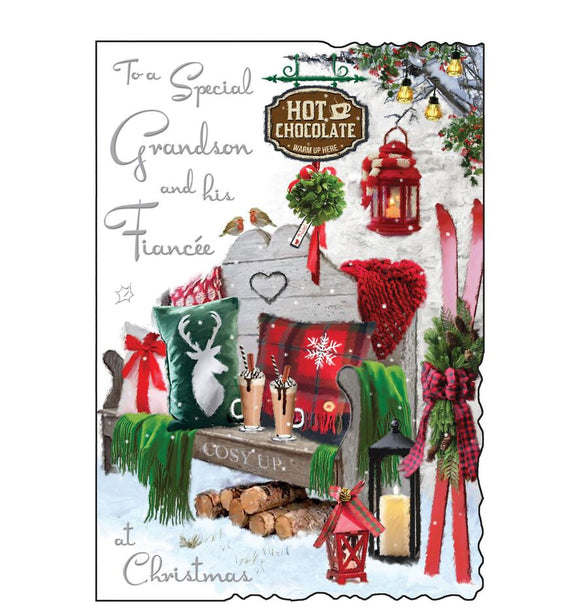 This Christmas card for a special grandson and fiancee is decorated with a scene of a snowy garden bench, made cosy with blankets, cushions and two festive hot chocolates. Silver text on the front of this Christmas card reads 