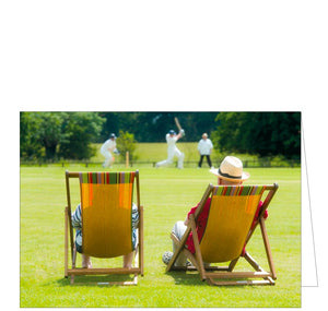 This blank greetings card is decorated with a photograph of two people sitting in deckchairs to watch a game of cricket.