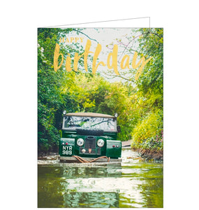This birthday card is decorated with a photograph of a landrover 4x4 car driving across a flooded road, with a tow rope tied to the front bumper, ready to rescue stranded cars. Gold text on the card reads "Happy Birthday".