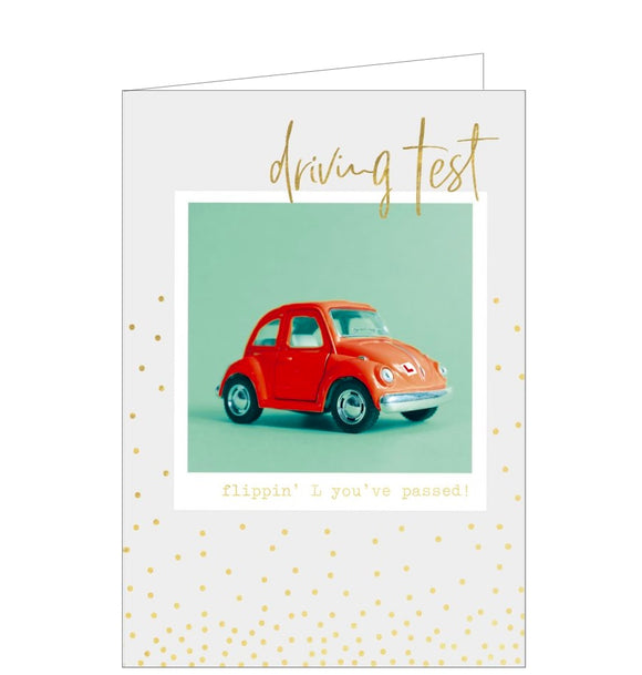 This congratulations card is decorated with a polaroid-style photograph of a brightly coloured little car. Gold script on the card reads “Driving test...flippin L you’ve passed”.
