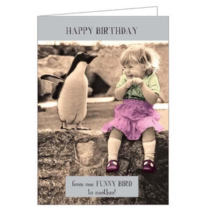 This funny birthday card features a photograph of a little girl sitting next to a penguin which is making her laugh. The caption reads "Happy Birthday...from one funny bird to another!"