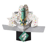 Pop-up 3D congratulations card shaped like a bottle of champagne overflowing with colourful confetti. The text on the front of this card reads "Congratulations".