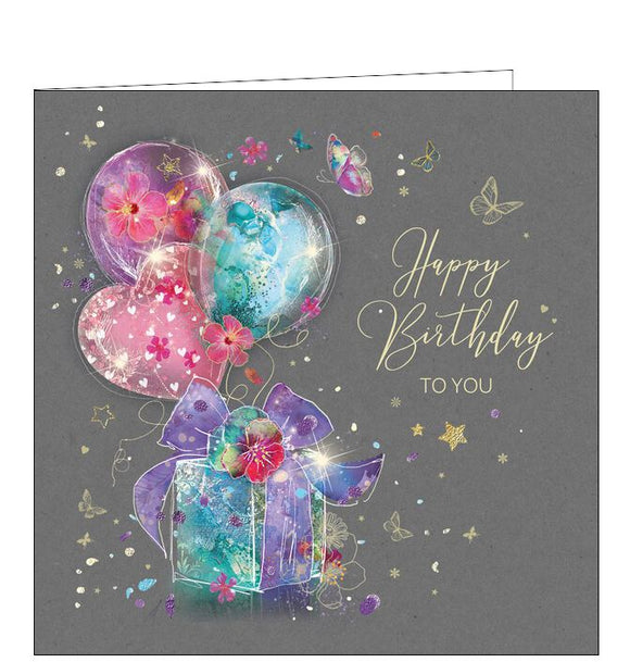 This birthday card is decorated with pink, purple and blue balloons tied to a coordinating birthday gift. Metallic gold text on the front of the card reads 