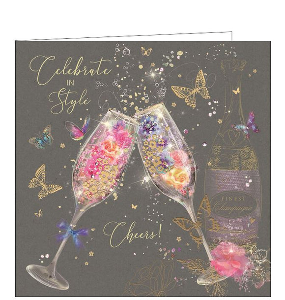 This birthday card is decorated with a pair of champagne flutes, filled with flowers and glittery bubbles. Metallic gold text on the front of the card reads 