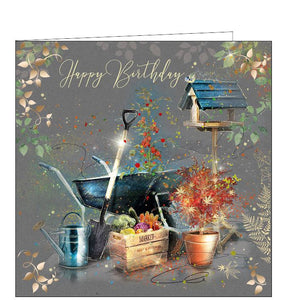 This birthday card is decorated with an arrangement of gardening tools - and beautifully grown home-grown vegetables. Metallic gold text on the front of the card reads "Happy Birthday".