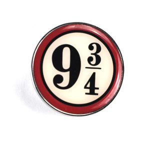 This circular enamel pin badge is decorated with the logo for Platform 9 3/4 - a cream-coloured circle with a red outline and black serif text that reads "9 3/4".