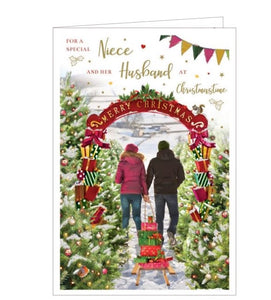 This beautiful Christmas card for a special niece and husband is decorated with a scene of a couple, pulling a sled loaded with gits, through a tunnel of christmas trees. The text on the front of the card reads "For a special Niece and her Husband at Christmastime".