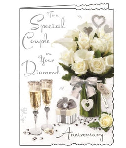 Jonny Javelin greetings cards combine beautiful, detailed illustrations with heartfelt words. This 60th Anniversary card is decorated with a table laden with flowers, champagne flutes, and 60th anniversary trinkets. The text on the front of the card reads "To a Special Couple on your Diamond anniversary"