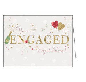 This lovely engagement card is decorated gold text that reads "You're Engaged Congratulations!"surrounded by tiny red and gold hearts, a bottle of champagne, and a pair of heart-shaped balloons