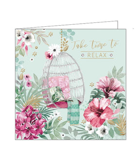 This lovely little card is decorated with a scene of a hanging basket chair, filled with cushions and blankets, surrounded by  pink, white and gold flowers. Gold text on the front of the card reads "Take time to relax".
