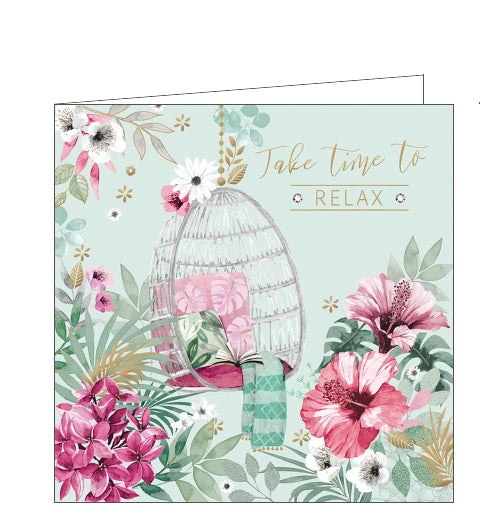 This lovely little card is decorated with a scene of a hanging basket chair, filled with cushions and blankets, surrounded by  pink, white and gold flowers. Gold text on the front of the card reads 