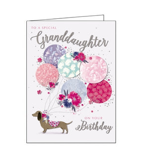This lovely birthday card for a special Granddaughter is decorated with an illustration of a little sausage dog in a pink patterned coat, with a collar of flowers. Tied to the dogs collar is a huge bunch of pink, purple and blue balloons. Text on the front of the card reads "to a special Granddaughter on your Birthday".
