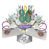 A spectacular pop-up 3D keepsake 80th birthday card, that opens to unleash purple streamers, gold glittery stars and text that reads "Happy 80th Birthday".