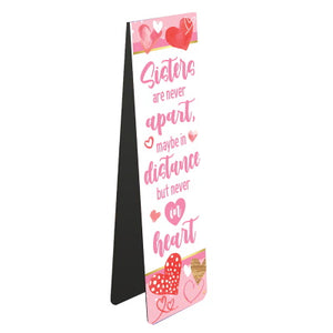 This magnetic book mark for a book-loving sister is decorated with pink hearts and pink text that reads "Sisters are never apart, maybe in distance but never in heart".