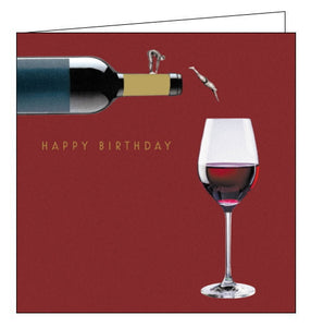 This birthday card is decorated with a bottle of red wine paused in the act of filling a glass with wine. Two figures stand on the wine bottle, one stretching and one diving into the glass of wine. Gold text on the front of the card reads "HAPPY BIRTHDAY".