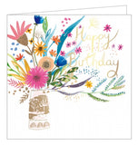 This lovely birthday card is decorated with a huge, brightly coloured bouquet of flowers in a gold vase. Gold text on the front of the card reads "Happy Birthday".