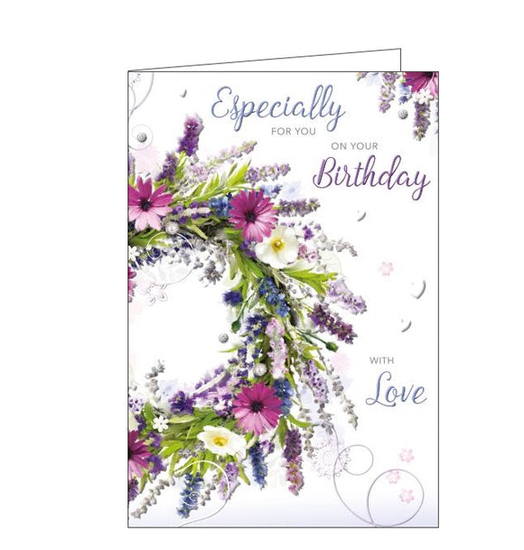 This lovely birthday card is decorated with a wreath of green foliage, blue, pink and purple flowers. Blue and purple text on the front of the card reads “Especially for you on your birthday...with love”.