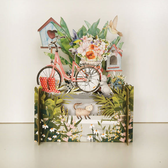 Perfect for a plant mum, this fabulous pop-up greetings card is made of multiple layers of laser cut card to create a wonderful 3d image of a pink bicycle - its back basket filled with flowers, surrounded by curious cats, birds and lots of flowers.