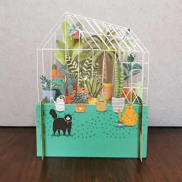 Perfect for a plant mum this fabulous pop-up greetings card is made of multiple layers of laser cut card to create a wonderful 3d image of a greenhouse filled with cacti and succulents. A pair of cats keep guard in front of the green house.